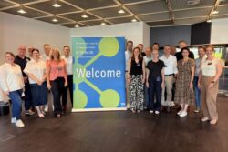 A group of participants in front of a K 2028 welcome banner in Düsseldorf during a workshop to prepare for the next plastics and rubber trade show